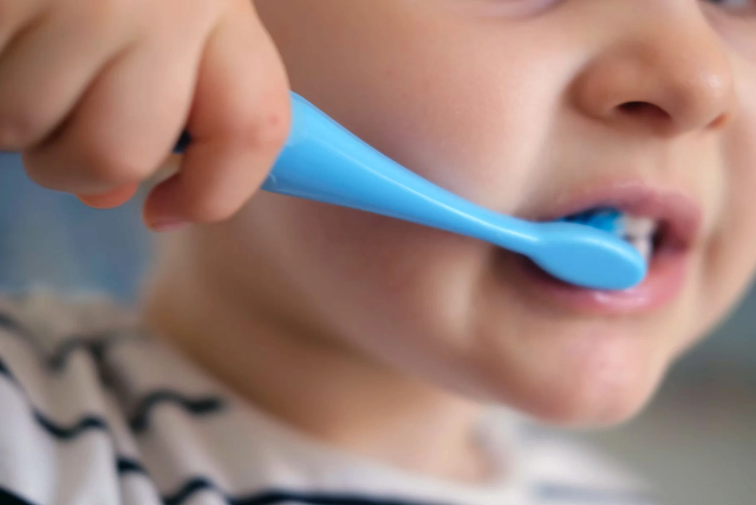 Child brushing teeth with blue toothbrush
