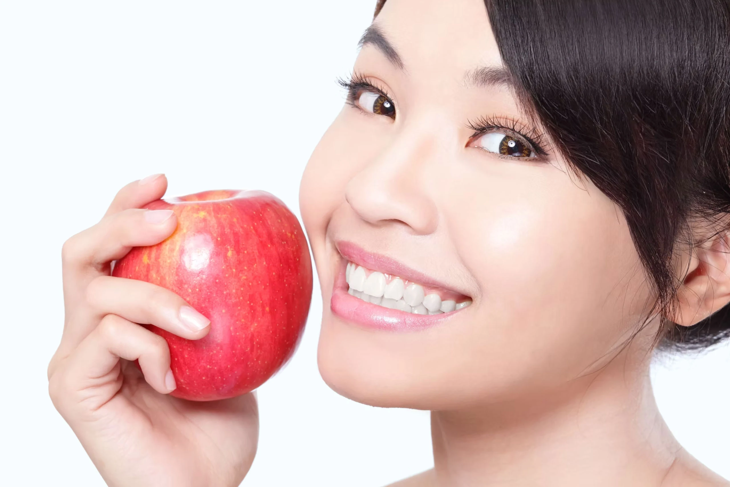 Woman smiling and holding an apple after dental visit