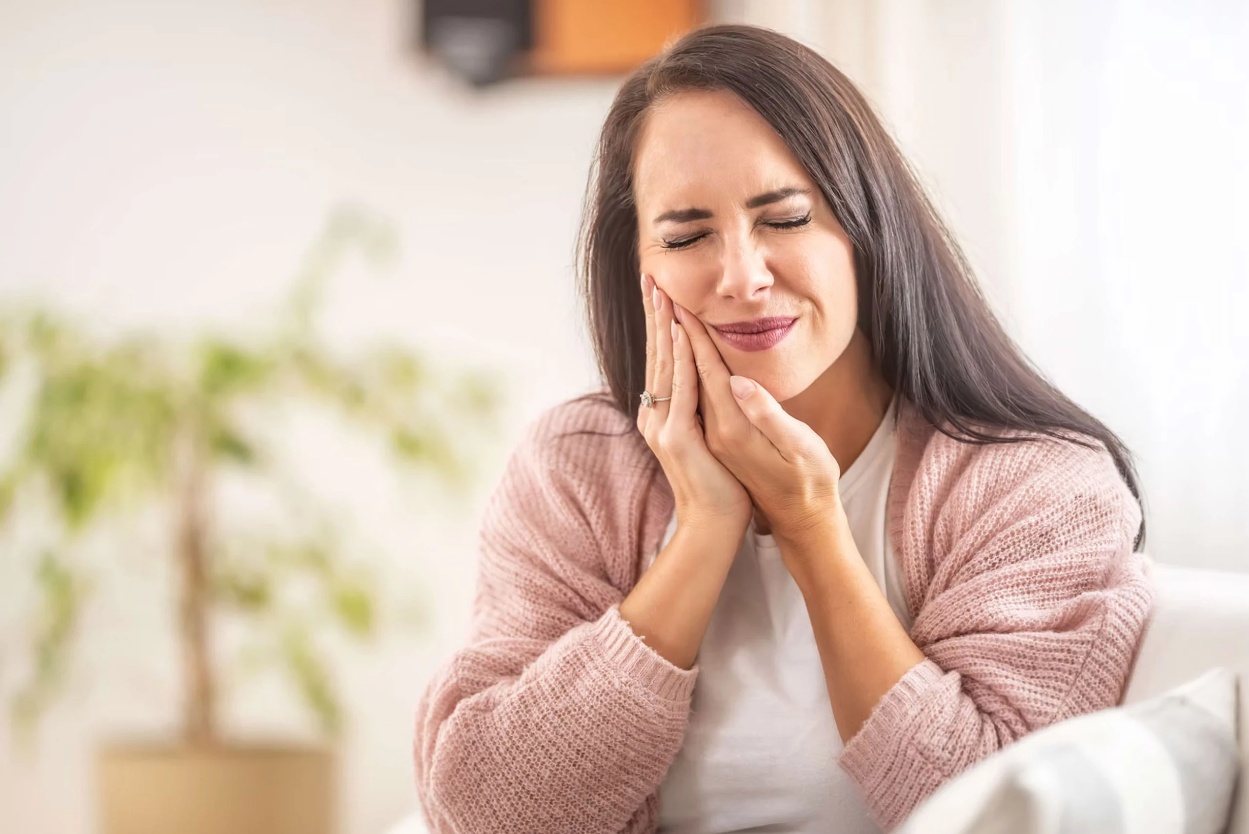 Woman holding jaw in discomfort, considering dental treatment